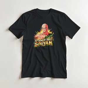 Puede incluir: Camiseta negra con un personaje musculoso con un tercer ojo, rodeado de energía amarilla y verde. El texto "MAXIMUM OVER SAIYAN" se muestra debajo. La camiseta está hecha de un material suave.
