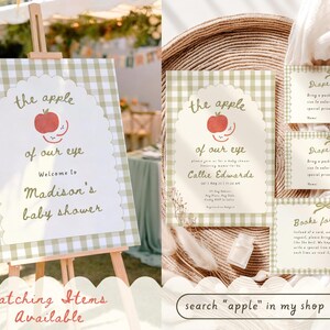 May include: A baby shower welcome sign on an easel and matching stationery set featuring a green gingham border, a scalloped white center, and red apple illustrations. The text reads the apple of our eye, Welcome to Madison's baby shower, Diaper Raffle, and Books for Baby.