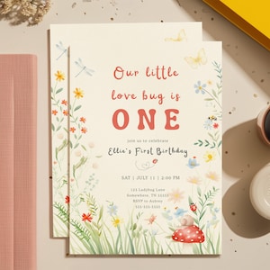 May include: A cream-colored birthday invitation with floral and insect illustrations. The text reads "Our little love bug is ONE" and includes event details. Watercolor style with butterflies, ladybugs, and flowers.
