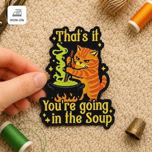 Op de afbeelding: Geborduurde opstrijkbare patch met een oranje tabby kat die in een ketel met groene vloeistof roert. De patch leest "That's it, You're going in the Soup" in gele tekst met zwarte contouren. De patch is omgeven door gele sterren en vlammen.