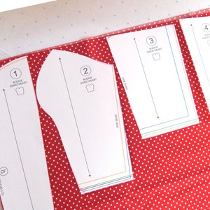 May include: Four white paper patterns for sewing a sweetheart bodice. The patterns are numbered 1 through 4 and are laid out on a red fabric with white polka dots.