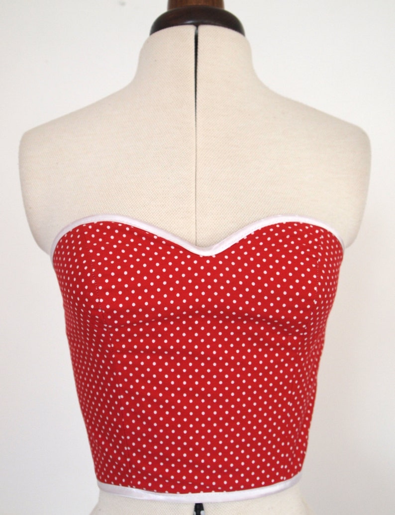 May include: A red strapless top with white polka dots and a white trim around the neckline.
