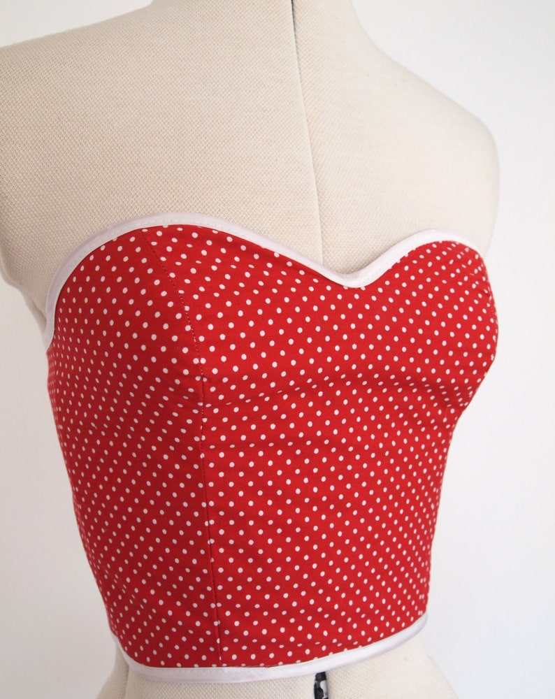 May include: A red strapless top with white polka dots and a white trim around the neckline.