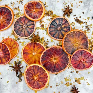 Bulk Dehydrated Blood Orange Slices - Dried Ruby Red Orange for Cocktails and Decor 80+ pieces on a tables spread out with herbs and spices in a very festive fall theme