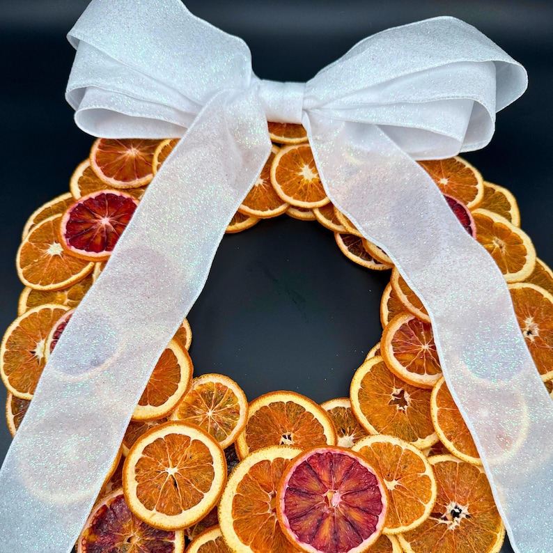 Our handcrafted Blood Orange Christmas Wreath combines rustic charm with modern elegance — each slice is air-dried to reveal that deep ruby hue only nature can create. Designed to bring a warm, citrus glow to your holiday décor, it’s the perfect accent for doors, mantels, or tablescapes. Bulk Dehydrated Blood Orange Slices - Dried Ruby Red Orange for Cocktails and Decor 80+ pieces on a wreath