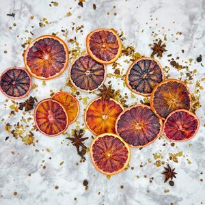 Bulk Dehydrated Blood Orange Slices - Dried Ruby Red Orange for Cocktails and Decor 80+ pieces on a tables spread out with herbs and spices simple and decorative