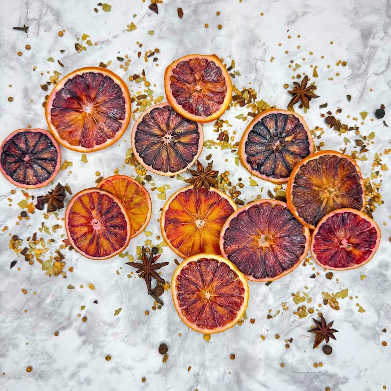 Bulk Dehydrated Blood Orange Slices - Dried Ruby Red Orange for Cocktails and Decor 80+ pieces on a tables spread out with herbs and spices simple and decorative