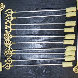 May include: A set of 14 fire staffs with gold-coloured metal tips and yellow fabric wrapped around the ends. The tips feature different decorative designs.