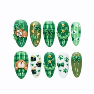 May include: A set of ten artificial nails with a St. Patrick's Day theme. The nails are primarily green, featuring designs like a bulldog wearing a leprechaun hat, shamrocks, gold coins, plaid patterns, and bows. Some nails have 3D embellishments.