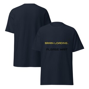 May include: A navy blue short-sleeve t-shirt featuring the yellow text "BRAIN LOADING..." and the black text "PLEASE WAIT" printed on the front. The garment is shown from both the front and back angles, displaying a simple crew neck design.