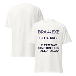 May include: A white short-sleeve t-shirt featuring the purple pixelated text BRAIN.EXE IS LOADING... and the black text PLEASE WAIT SOME THOUGHTS FAILED TO LOAD. The shirt is displayed from both the front and back angles, showing a plain white back.