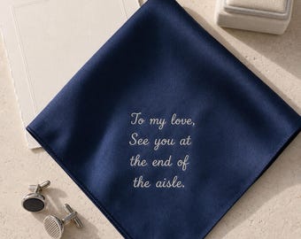 May include: A navy blue square pocket square featuring white embroidered text that reads, To my love, See you at the end of the aisle. The fabric has a smooth, satin-like finish and is accompanied by a pair of silver-toned metal cufflinks.
