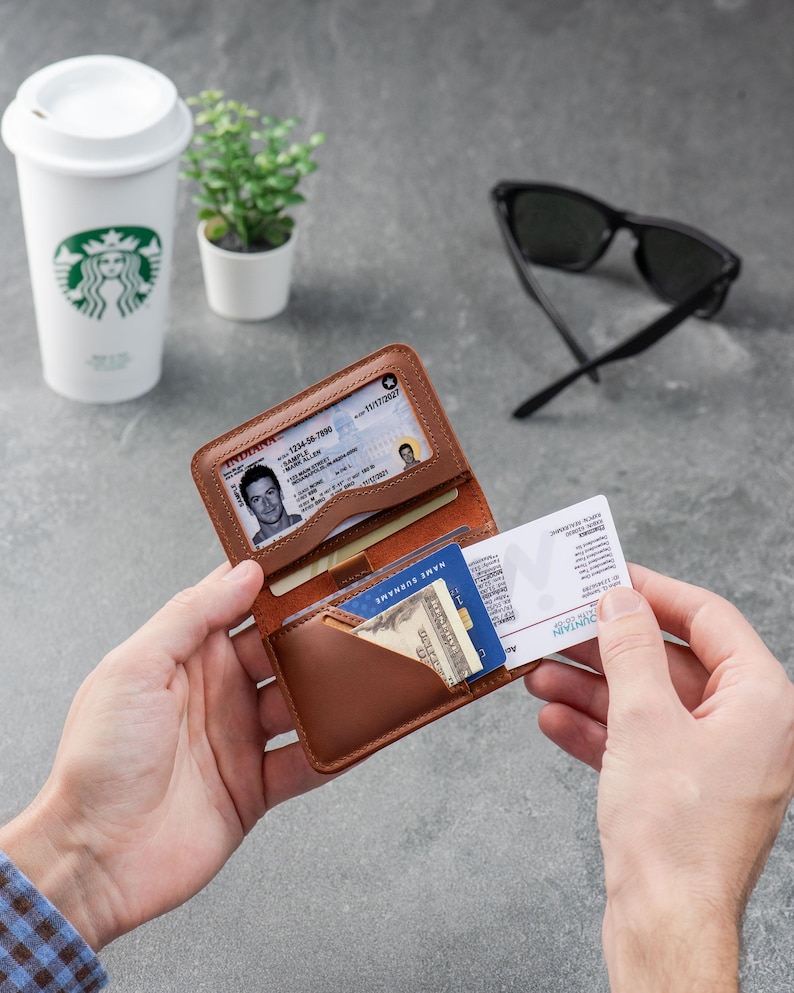 Leather ID wallet open on a desk with cards and coffee cup in the background