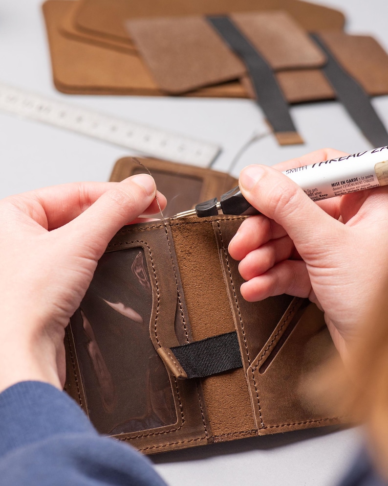 Hands crafting and stitching the men’s leather wallet during production