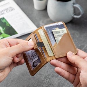Man holding slim leather card holder wallet and sliding an ID from the clear window