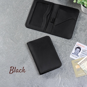 Black leather minimalist wallet with ID window and card slots on a gray background