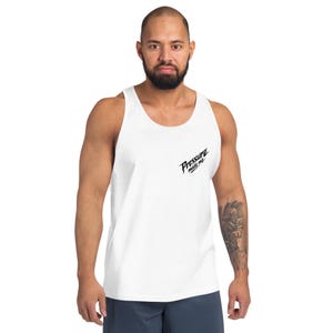 May include: White tank top with the text "Pressure made me" in black script on the upper left chest. The tank top is sleeveless and made of a soft material. The model is wearing blue shorts.