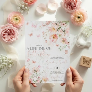 May include: A baby shower invitation with a floral and butterfly design. The invitation features the text "Here's to a lifetime of butterflies" and event details. Soft pink and white colors are used throughout the design.