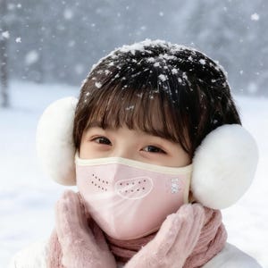 May include: A young person wearing a pink face mask with a cartoon character design and white earmuffs in a snowy environment. The mask has a breathable vent design. The person is also wearing pink gloves and a scarf.