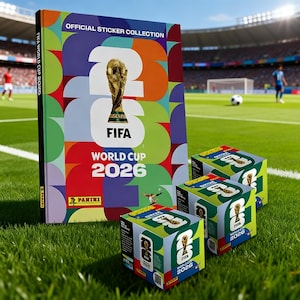 May include: An official FIFA World Cup 2026 sticker collection album and three boxes of stickers are displayed on a green field. The album cover features the FIFA trophy and the text "FIFA World Cup 2026". The boxes also display the FIFA logo and the year 2026.