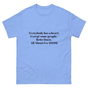 Peut inclure: T-shirt bleu clair avec la citation "Everybody has a heart. Except some people." attribuée à Bette Davis du film All About Eve (1950). Le texte est en noir.