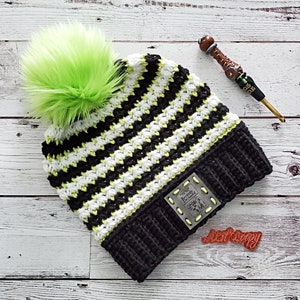 May include: Black and white striped crochet hat with a lime green pom pom. The hat has a black crocheted brim and a metal label that says "Second Decade".