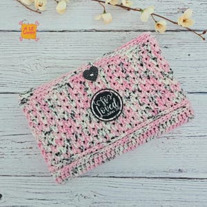 Pode incluir: Uma clutch de croch&ecirc; feita &agrave; m&atilde;o em rosa, branco e preto. Possui um bot&atilde;o em forma de cora&ccedil;&atilde;o e um patch circular que diz "So Loved John 3:16". Apresentada em uma superf&iacute;cie de madeira clara.