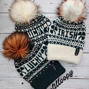 May include: Three knitted winter hats with pom poms. The hats are green, white, and brown with a fair isle pattern. The hats have the words "Lucky", "Irish", and "Autumn" written on them.