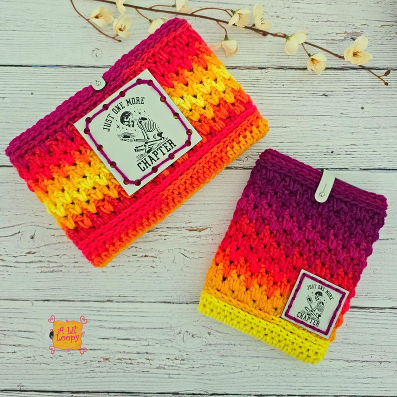 Pode incluir: Duas capas de livro de croch&ecirc; em cores vibrantes, incluindo rosa, laranja e amarelo. Cada capa tem um r&oacute;tulo que diz "Just One More Chapter" com um gr&aacute;fico de esqueleto. Uma capa tem um fecho de bot&atilde;o.