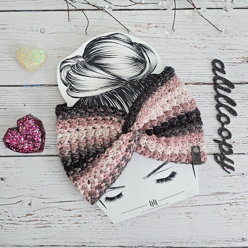 Puede incluir: Una diadema de crochet rosa, negra y blanca con un lazo. La diadema est&aacute; sobre una tarjeta blanca con un dibujo de cabello de mujer y el texto "allcoops".
