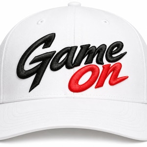 Pode incluir: Um boné de beisebol branco com o texto bordado Game on na parte frontal. A palavra Game é costurada com linha preta, enquanto a palavra on é costurada com linha vermelha. O boné possui uma copa estruturada e uma aba curva.