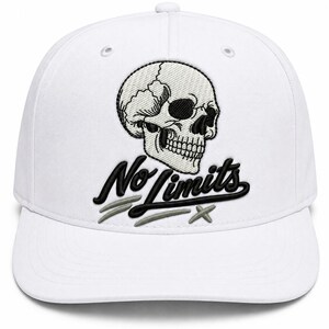 May include: A white baseball cap featuring an embroidered black and white skull graphic positioned above the black text No Limits. Below the text are three small, light gray embroidered marks resembling stylized slashes or cross symbols.