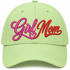 May include: A light green baseball cap featuring the embroidered text Girl Mom in a cursive font. The word Girl is stitched in bright pink with a small heart above the letter i, and the word Mom is stitched in red with a heart below it.