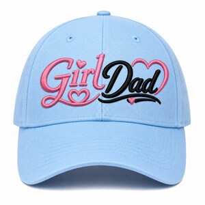 Op de afbeelding: Een lichtblauwe baseballpet met geborduurde tekst die Girl Dad leest. Het woord Girl is in roze gestikt met een klein hartje boven en onder de letters. Het woord Dad is in zwart gestikt met een roze hartomtrek en een klein roze hartje.