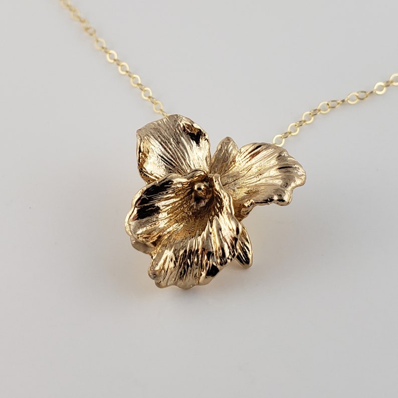 May include: A gold flower pendant necklace. The pendant is a detailed, three-dimensional design of a flower with five petals.