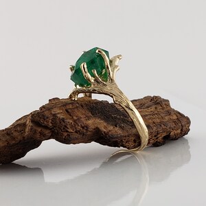 Puede incluir: Un anillo de oro con una gran esmeralda verde engastada en un dise&ntilde;o de rama.