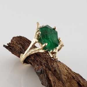 Puede incluir: Un anillo de oro con una gran esmeralda facetada engastada en un dise&ntilde;o de rama.