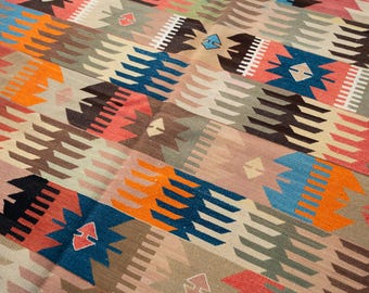 Può includere: Un tappeto fantasia con un design geometrico in vari colori. Il tappeto presenta tonalità arancioni, blu, rosa e marroni. Il design incorpora forme e motivi geometrici ripetuti, creando un tessuto visivamente accattivante.
