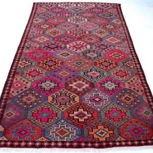 May include: A rectangular area rug featuring a repeating geometric pattern of interconnected hexagons and diamonds in vibrant shades of hot pink, deep purple, orange, and teal, finished with a dark maroon border and short white fringe at both ends.