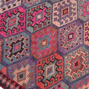 May include: A woven rug featuring a repeating pattern of interconnected hexagons in vibrant shades of hot pink, deep purple, teal, orange, and dark brown. Each hexagon contains intricate geometric diamond motifs and small linear details.