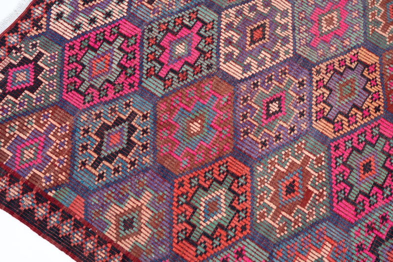 May include: A woven rug featuring a repeating pattern of interconnected hexagons in vibrant shades of hot pink, deep purple, teal, orange, and dark brown. Each hexagon contains intricate geometric diamond motifs and small linear details.