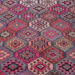 May include: A woven rug featuring a repeating geometric pattern of interconnected diamonds and octagons. The design incorporates a vibrant color palette of hot pink, deep purple, teal, orange, and black, with intricate small-scale cross-stitch details.