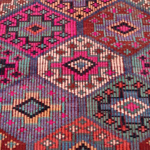 May include: A woven textile featuring a repeating geometric pattern of interconnected diamonds and hexagons. The design incorporates a vibrant color palette of hot pink, deep red, teal, navy blue, and cream, creating a dense, textured surface.