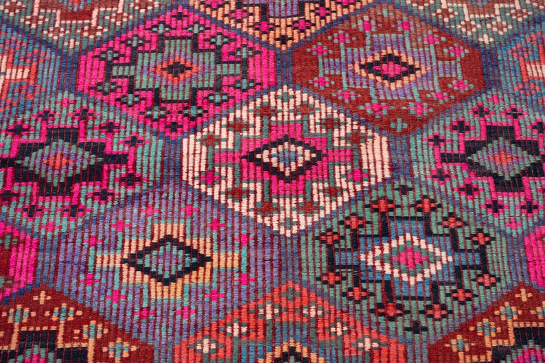 May include: A woven textile featuring a repeating geometric pattern of interconnected diamonds and hexagons. The design incorporates a vibrant color palette of hot pink, deep red, teal, navy blue, and cream, creating a dense, textured surface.