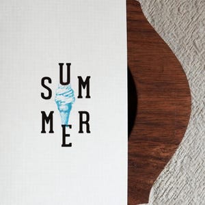 May include: A white rectangular card with a faint grid pattern features the black text SUMMER arranged vertically and horizontally around a central light blue watercolor illustration of a soft serve ice cream cone in the middle of the word.