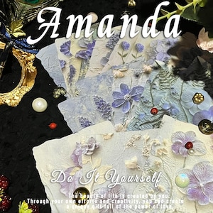 May include: A collection of textured, light blue and white floral art cards with the word "Amanda" in white script. The cards feature embossed flowers and the text "Do It Yourself". Decorative elements include a peacock feather and pearls.