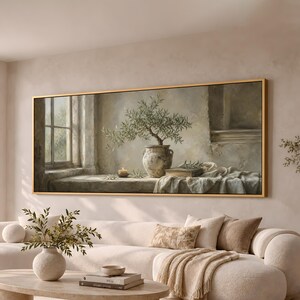 May include: A rectangular wall art piece in a gold frame depicting an olive tree in a weathered ceramic pot, a lit candle, and a book resting on a stone ledge near a window, all rendered in muted earth tones and soft light.