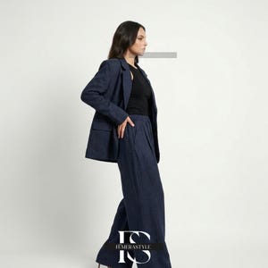 May include: A dark blue blazer and matching wide-leg trousers set worn over a black sleeveless top. The blazer features notched lapels and two front pockets. The trousers have a high-waisted fit with a pleated front design and a loose silhouette.
