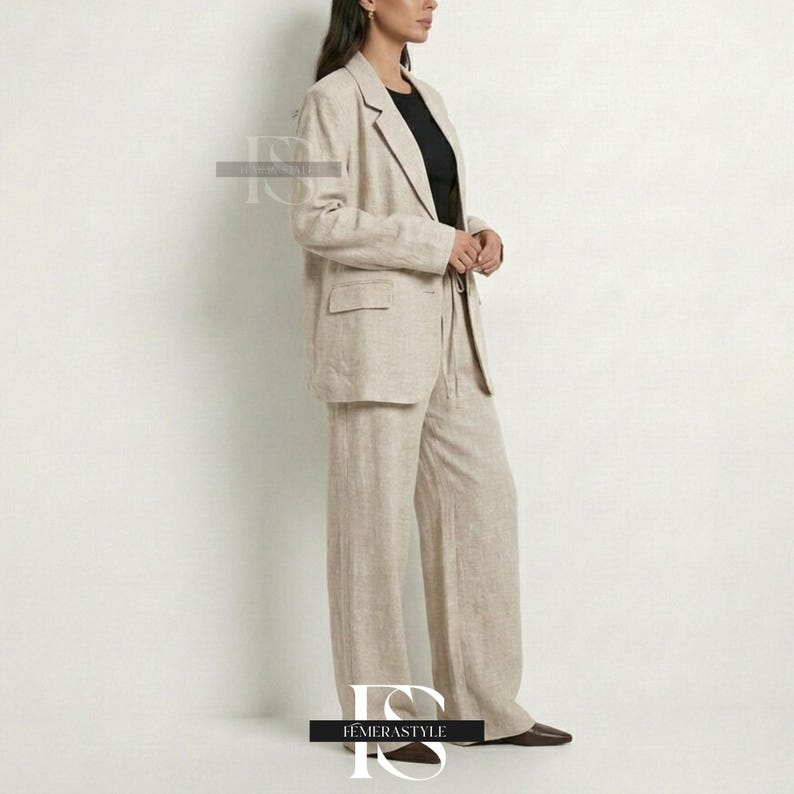 May include: A beige linen blazer and matching wide-leg trousers set. The blazer features a notched lapel, long sleeves, and two front flap pockets. The trousers have a relaxed, straight-leg fit. A black top is worn underneath the blazer.
