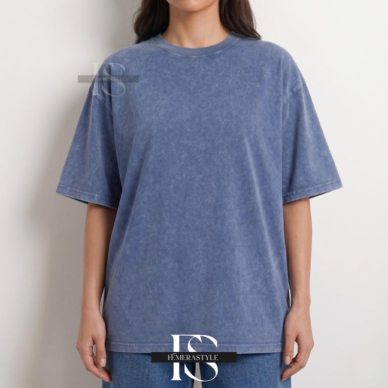 Pu&ograve; includere: Una maglietta blu a maniche corte con un aspetto strutturato e sbiadito. La maglietta ha un girocollo e una vestibilit&agrave; ampia. La modella indossa jeans blu. La maglietta &egrave; del marchio Iemerastyle.